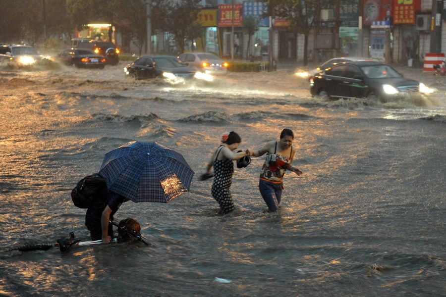 6月23日傍晚，行人从严重积水的洛阳市太原路与联盟路交叉口经过。新华社发（杨帆 摄）
