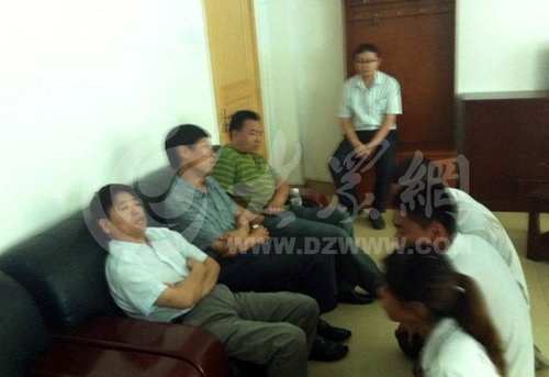 在寿光市人民医院接待室，3名死者家属向院方人员下跪，院方人员表情漠然。