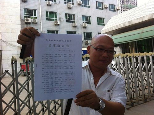 药庆卫代理人马延明在法院门口向记者展示裁定书（来源：王甲铸摄）