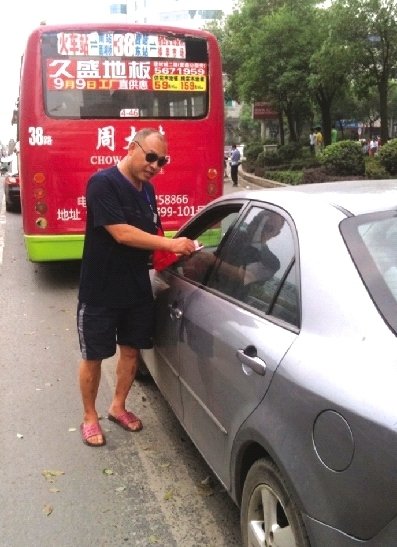 8月17日，邵阳市西湖路与宝庆路交接处，穿拖鞋戴墨镜的市容监督员在对占压斑马线停放的车辆罚款。图/记者龙源