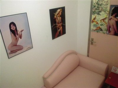 取精室内，有一个粉色沙发，墙壁四周挂着女体画