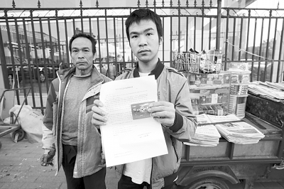 昨天下午张龙和父亲在报摊前对银行巨额还款一筹莫展。记者杨涛摄