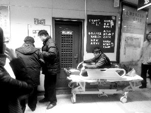 受伤工人小王坐在病床上候诊。