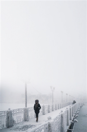 一名女子走在奥伊米亚康一座冰封的桥上