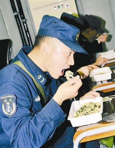 “青岛”舰上的官兵在战位上吃野战快餐。解放军报 记者 米晋国摄