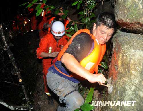 一名网名叫“烟花”的游客(右一)在救援人员的帮助下走出峡谷。新华社发(李进发摄)