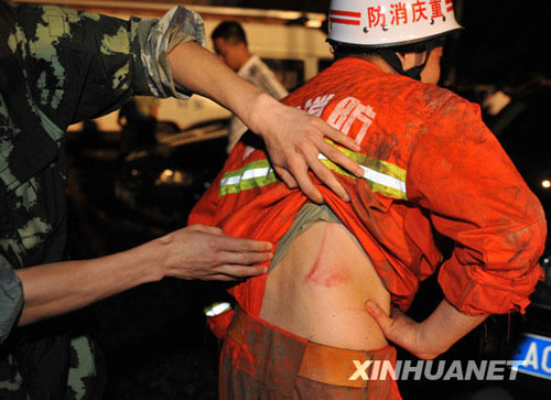 搜救人员在察看战友被山石划破的伤口。新华社发(李进发摄)