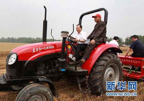 6月10日，在河南省许昌县陈曹乡后孙汪村高产小麦示范区，中共中央政治局常委、国务院总理温家宝登上一台“东方红”牌拖拉机的驾驶室，在司机的指导下挂挡、加油，紧握方向盘，稳稳地驾驶着，在刚刚收割的麦地里深耕、施肥，种下秋玉米。新华社记者庞兴雷摄 