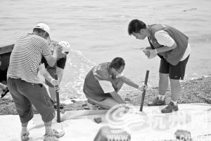 大连市黑石礁，志愿者试图阻拦油污。