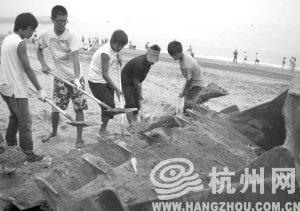 大连市金石滩国宾浴场,工作人员将带有油污的沙子清理掉。