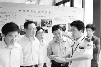 图为公安部经侦局副局长高峰(右)向公安部特邀监督员们介绍“亮剑”行动展览情况。