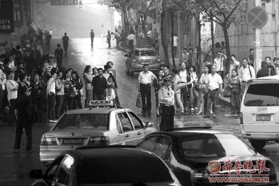  8日，在青岛15中考点外，家长排起人墙堵路，交警只能指挥途经车辆绕行。 本报记者 杨宁 张晓鹏 摄
