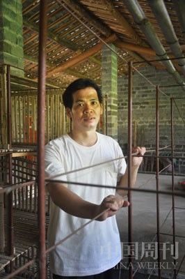 杨盛敏站在空置的兔笼前，兔笼是父母曾经关他的铁笼改造的。摄影闫小青。