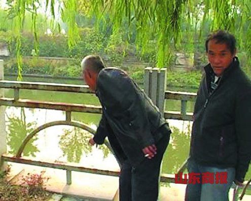 目击者给记者指认孩子落水的位置。