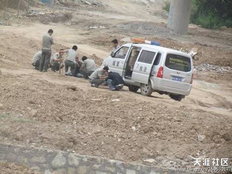 陕AWK707的西安城管执法车和6名穿制服的城管，手持棍棒，在郊外殴打两名倒地男子。 