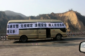 山西旧关收费站事发现场，死者家属在中巴车上挂起横幅讨说法。图/山西高速交警一支队