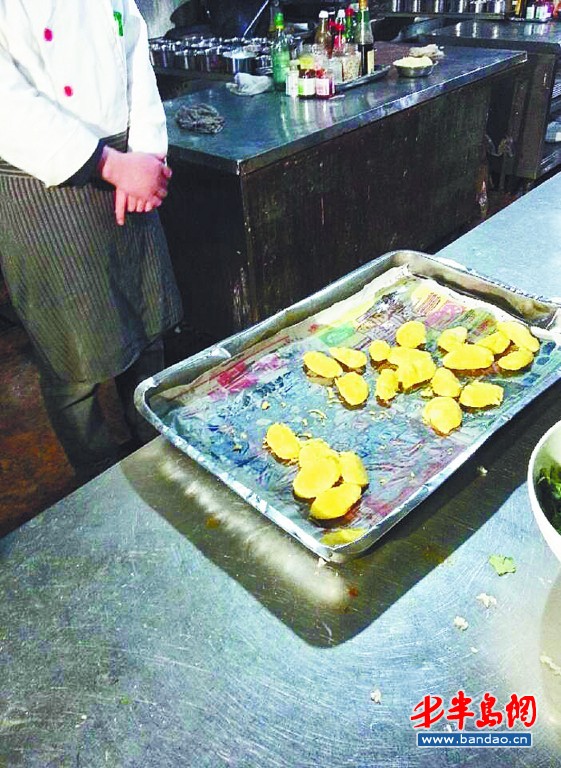 小渔村海鲜码头酒店将炸好的山药放在报纸上。