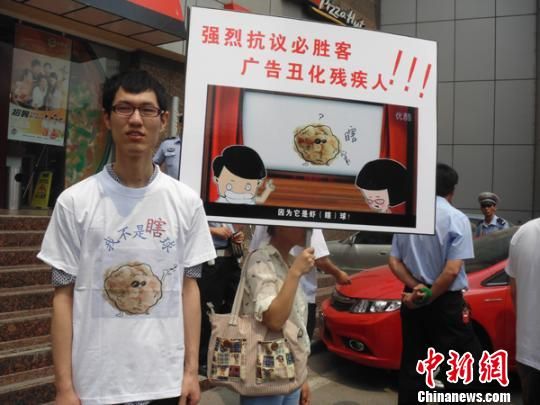 6月5日，视障人士在郑州一必胜客门前举牌抗议虾球广告歧视。 门杰丹 摄