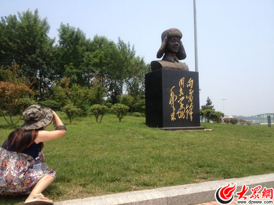 “聚焦美丽山东——第九届中国网络媒体山东行”南线采访团来到日照好人广场，图为记者在用摄像头记录好人广场上的雷锋雕像。